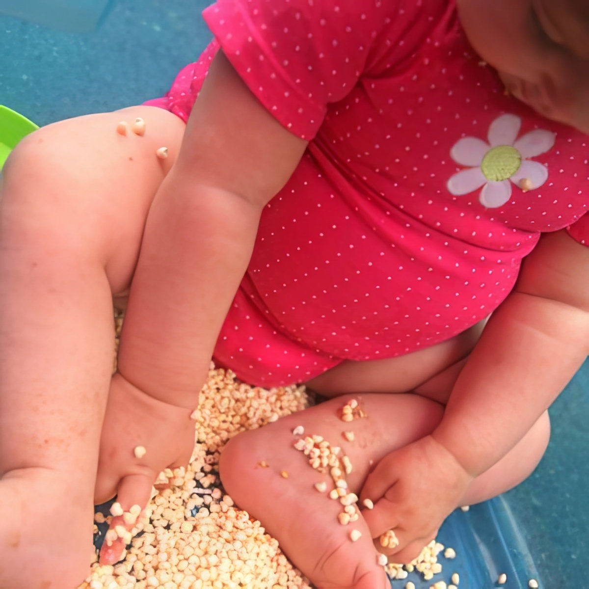 baby playing with cereal as sensory bins for preschoolers
