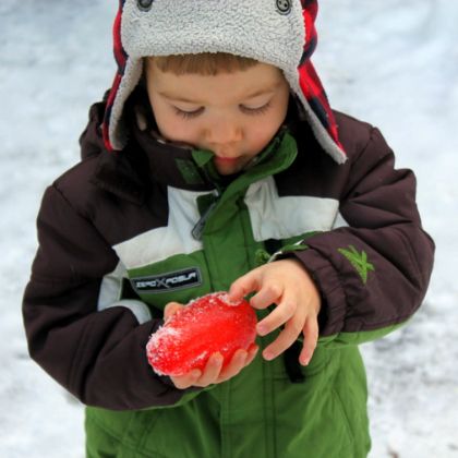 kid holding an ice jewel to decorate a snow man as outdoor games to burn off steam