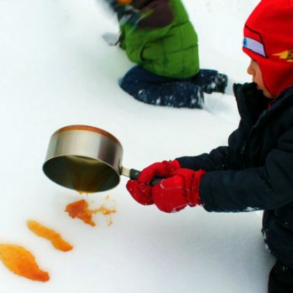 kid pouring homemade maple candy onto the snow as outdoor games to burn off steam