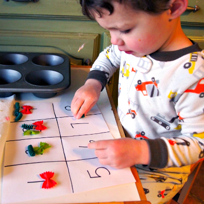noodle counting - boy using numbers on paper as guide for knowing how many pasta pieces to put