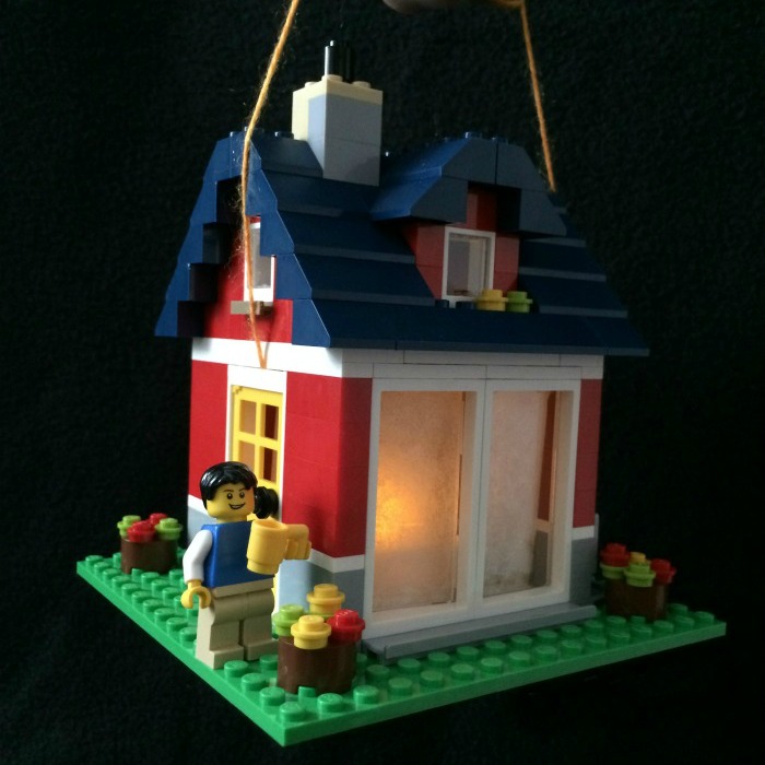 Lego Lantern activity for kids. House-shaped Lego Lantern with a Lego man watering the plants outside