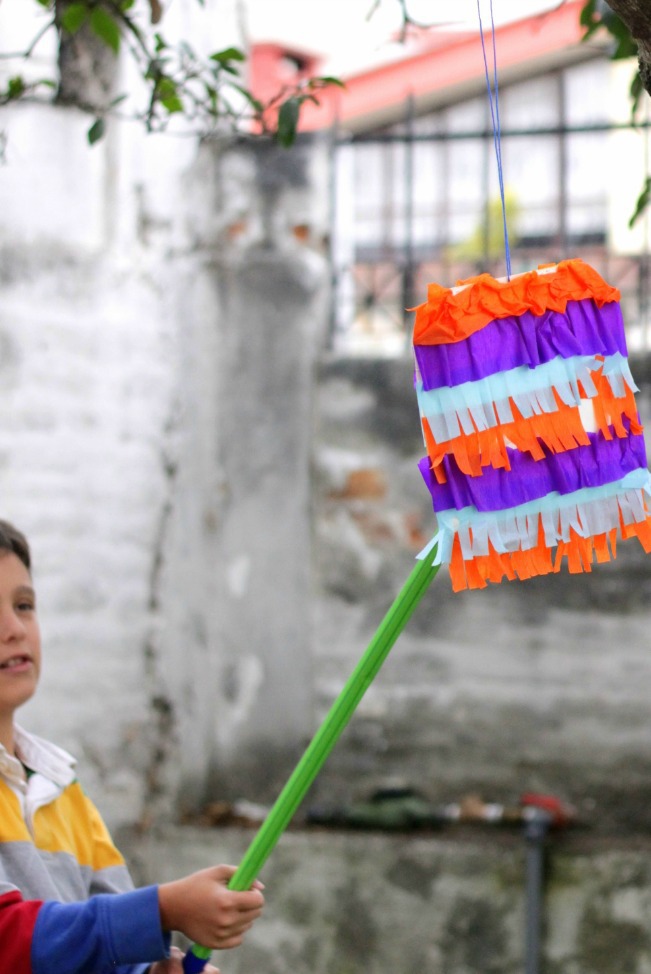 pinata made from paper plates shown with child hitting hung from tree